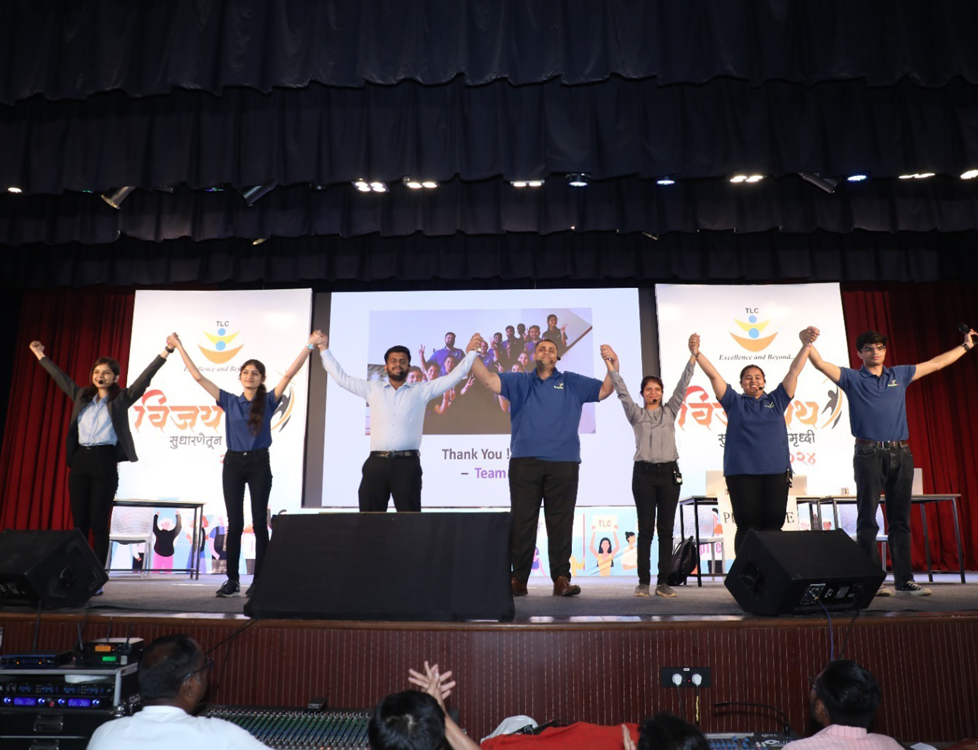 Team-on-stage-holding-hands-at-TLC-event